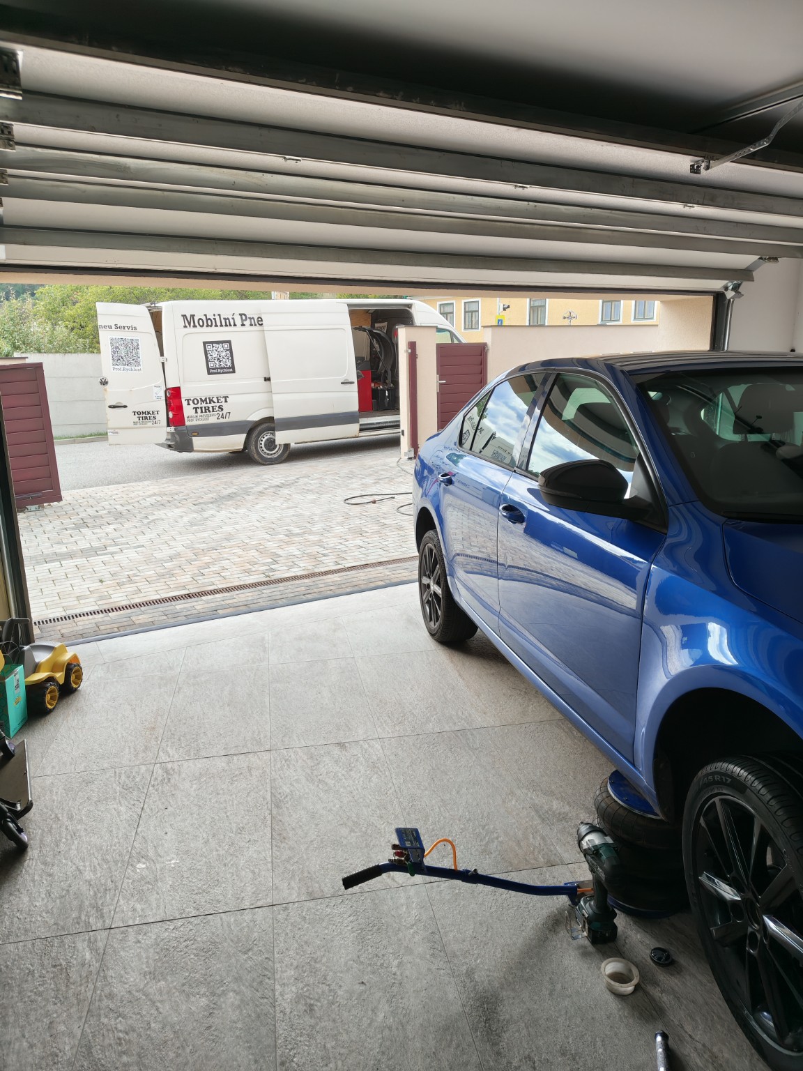 Modré auto a servisní dodávka u domu