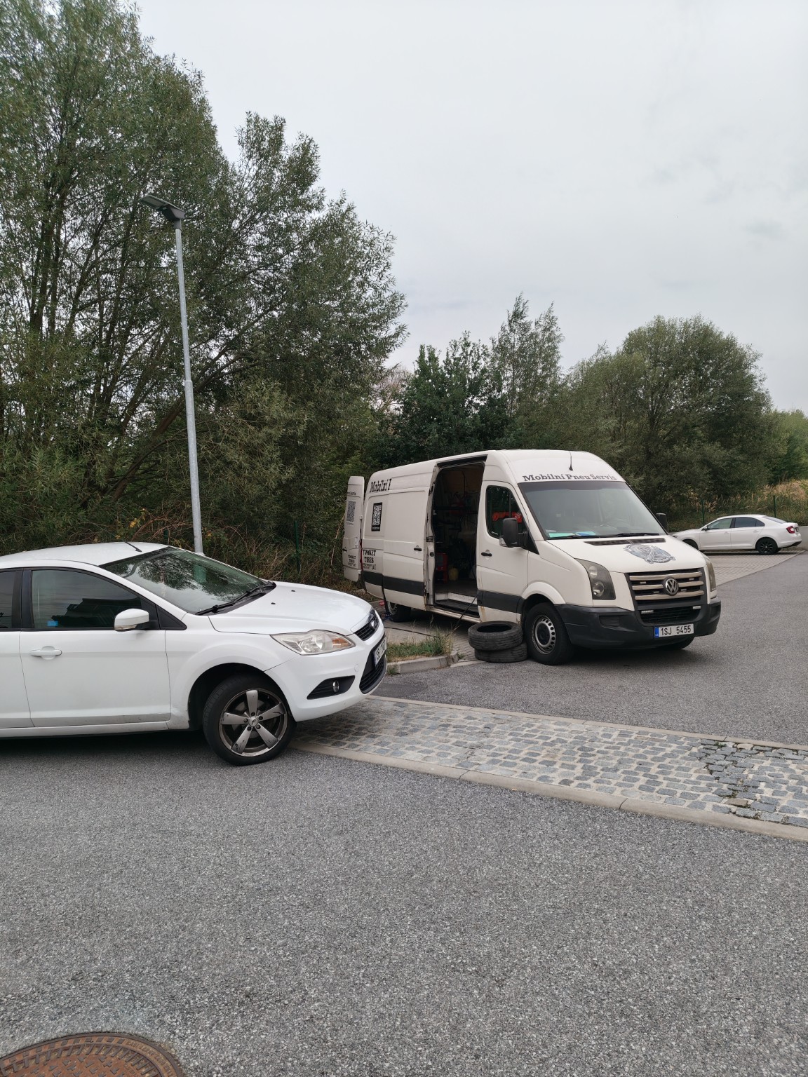 Bílé auto a servisní dodávka na parkovišti