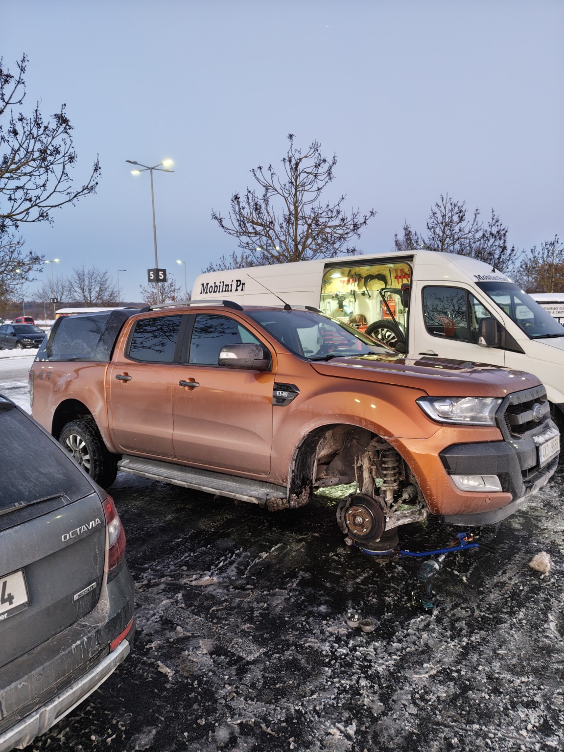 Práce u oranžového auta v zimě