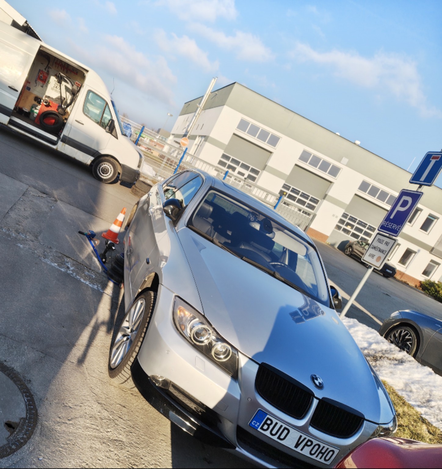 Stříbrné auto u servisní dodávky